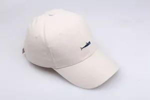 Close-up of small navy whale embroidery on beige cotton baseball cap with fine stitching