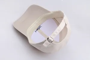 Detailed view of fish embroidery and adjustable metal buckle on a beige cotton baseball cap