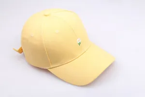 Détail de la broderie de marguerite sur la casquette de baseball en coton jaune