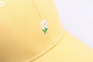 Gros plan d'une broderie de marguerite sur une casquette de baseball en coton jaune de qualité