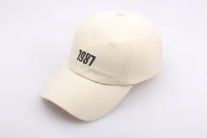 Nahaufnahme der schwarzen 1987-Stickerei auf einer cremefarbenen Baumwoll-Baseballkappe