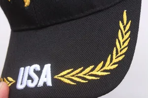 Detailed macro view of white USA embroidery and golden laurel leaves on black cotton cap brim