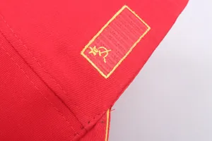 Macro view of high-quality yellow Soviet hammer and sickle embroidery on red cotton hat