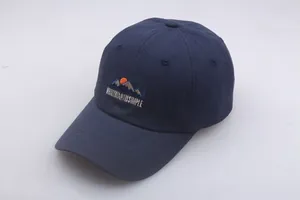 Close-up of mountain embroidery and artistic text on a navy cotton baseball cap