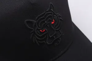 Makroaufnahme der detaillierten schwarzen Tiger-Stickerei mit roten Augen auf einer Cap