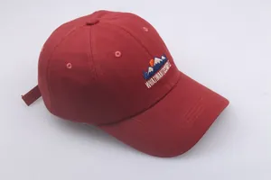 Detailed close-up of mountain embroidery and text on a burgundy cotton baseball cap