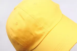 Detail einer gelben Baseballkappe aus Baumwolle mit Luftlöchern und Knopf oben