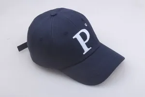 Détail de la lettre P brodée en blanc sur une casquette en coton bleu marine aux points nets