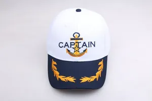 Dettaglio del berretto da capitano bianco con ancora dorata e visiera blu scuro