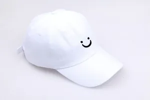 Detail van zwart smiley-borduurwerk op een witte katoenen verstelbare honkbalpet
