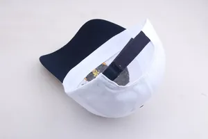 Dettaglio del cinturino regolabile in velcro e visiera blu navy su cappello bianco