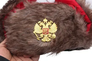 Detail der braunen Uschanka aus Kunstpelz mit goldenem russischen Wappen und rotem Futter