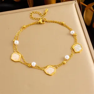 Detail of double-layer gold chain anklet featuring starfish pearl and shell charms