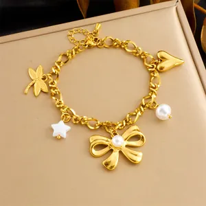 Dettaglio di bracciale dorato a strati con ciondoli a libellula, cuore e farfalla di perla