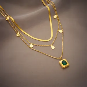 Detail of layered gold necklace with emerald-green stone and water-drop pendants