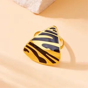 Macro view of gold triangle ring featuring black enamel animal print patterns