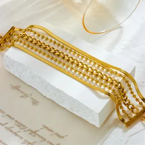 Multi-layer gold chain bracelet with snake and bead links on a white stone background