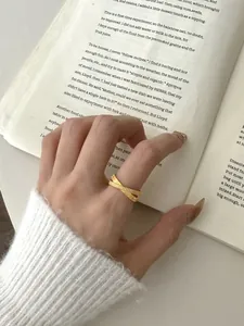 Dettaglio di un anello incrociato placcato oro con trama intrecciata su uno sfondo libro