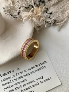Dettaglio dell'anello d'oro vintage con tre file di rubini e diamanti e bordi zigrinati