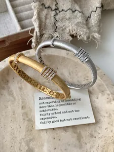 Detalle de brazalete cepillado en oro y plata con circonitas y patrones calados