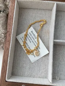 Detailed macro of gold-plated silver beaded bracelet with clover and oval pendants