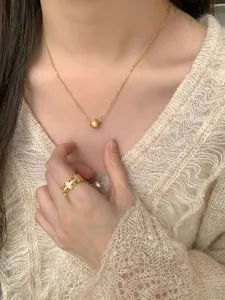 Détail d'un collier à perle dorée et d'une bague ajourée avec diamants sur un modèle