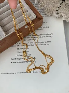 Close-up of a multi-layer gold S925 silver waterfall necklace held over a vintage box