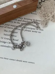 Close-up of S925 silver beaded bracelet with clover pendant and gemstone on retro paper