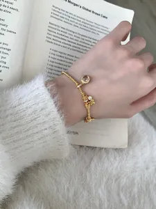 Close-up of a gold-plated beaded bracelet with crystal and spiral texture charms