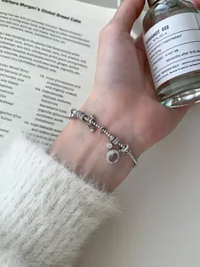 Detail of beaded S925 sterling silver bracelet with lavender gemstone and charms on wrist