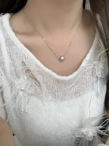 Détail du collier en argent S925 avec pierre bleue sur un pull blanc élégant