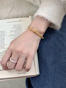 Close-up of a gold beaded charm bracelet with bear pendant and silver pavé ring