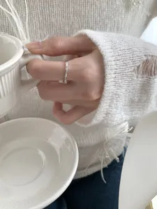 Detalle de anillo de plata S925 estilo bambú con cristales sobre fondo blanco suave
