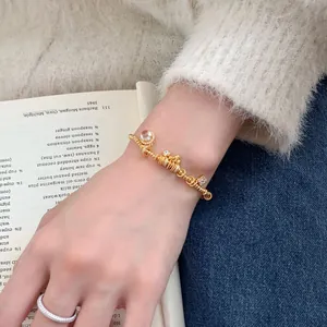 Elegant gold S925 silver bracelet with heart and pink gemstone pendants on a model's wrist
