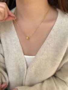 Gedetailleerd beeld van een S925 zilveren cilinderhanger aan een gouden bolletjesketting