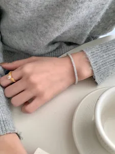 Macro detail of silver pave bracelet and gold pear cut ring on a model's wrist