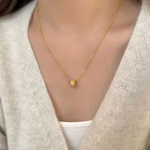 Elegante gouden S925 zilveren ketting met cilindervormige hanger gedragen door een model