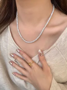 Vue portée d'un collier pavé en argent texturé et d'une bague fleur dorée évidée