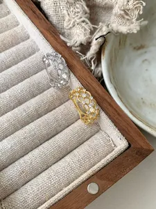 Close-up of gold and silver lace rings with zircon stones on wooden display tray