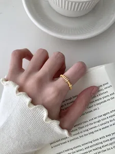 Dettaglio di un anello d'oro con texture spazzolata e zirconi sulla mano di una donna