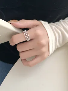 Detailed close-up of a hollow woven silver lace ring with micro-set crystal accents