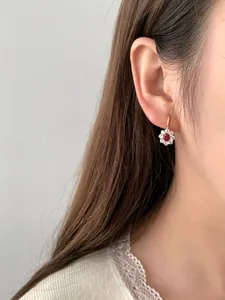 Primo piano di orecchini a girasole in argento S925 con rubino e zirconi indossati