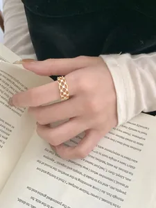 Detail of a gold lace hollow ring with small crystals worn while holding a book