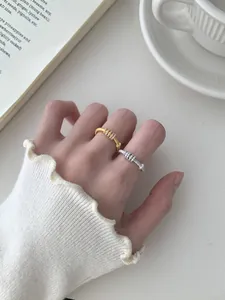 Macro di anelli spazzolati argento e oro con zirconi micro-incastonati sulla mano della modella