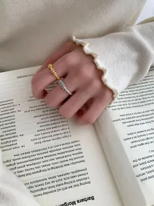 Dettaglio di anelli a spirale in argento e oro con diamanti indossati sulla mano