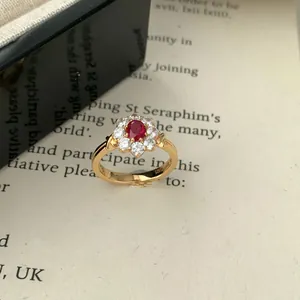 Anello girasole in argento S925 con rubino rosso su pagina di libro d'epoca