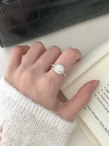Close-up of S925 sterling silver halo ring with moissanite center stone on model hand