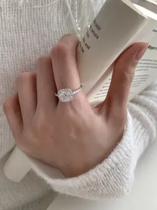 Close-up of S925 sterling silver halo ring with a round moissanite on a knit sleeve background