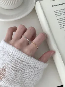 Close-up of minimalist S925 silver and gold rings with small diamonds on model