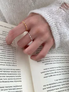 Close-up of minimalist gold and silver S925 rings with tiny crystals on a book